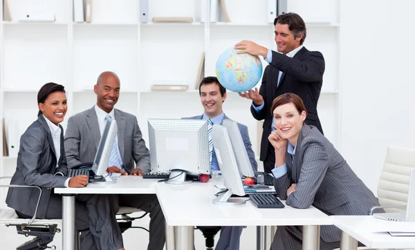 계산에서 일 하는 그의 팀과 함께 지구를 들고 웃는 관리자 — 스톡 사진