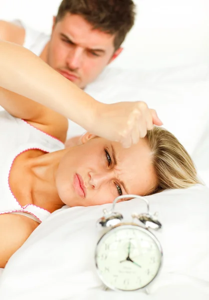 Homem e mulher zangada na cama olhando para o despertador disparando — Fotografia de Stock