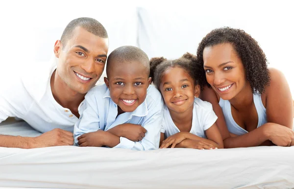 Happy family having fun lying down on bed — Stock Photo, Image