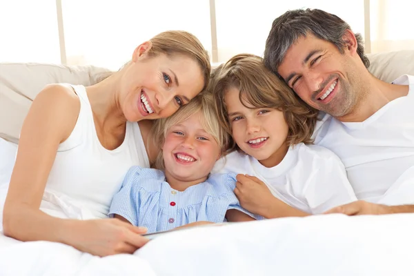 Glückliche Familie liest ein Buch auf dem Bett — Stockfoto