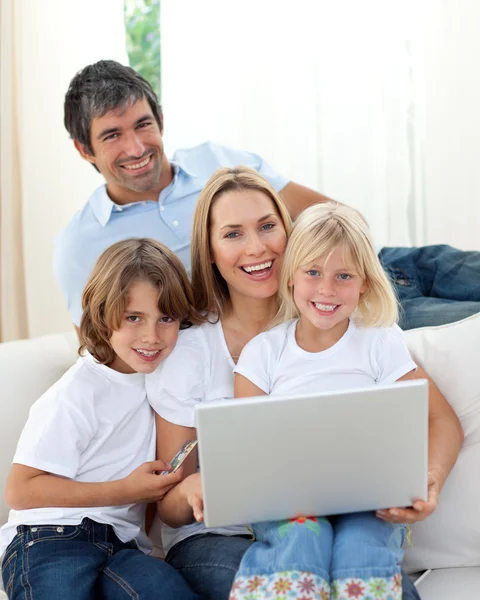 Söta barn med sina föräldrar som använder en bärbar dator — Stockfoto
