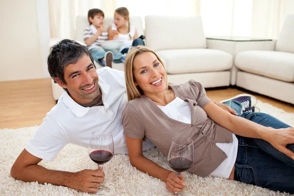 Affectionate lovers drinking wine lying on the floor — Stock Photo, Image