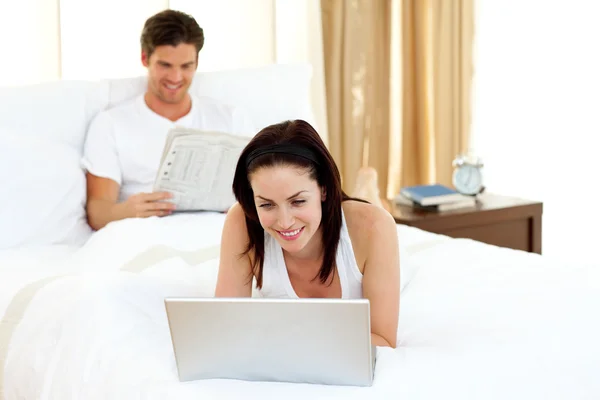 Frau benutzt Laptop auf ihrem Bett — Stockfoto