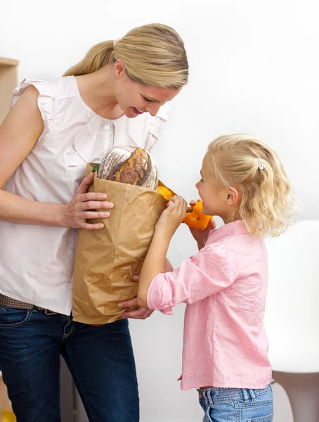 Little girl unpacking grocery bag with her mother — Stock Photo, Image