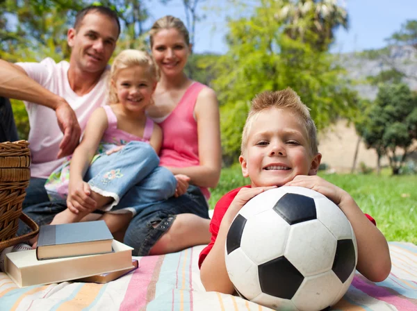 Niño divirtiéndose con una pelota de fútbol con su familia sonriendo —  Fotos de Stock