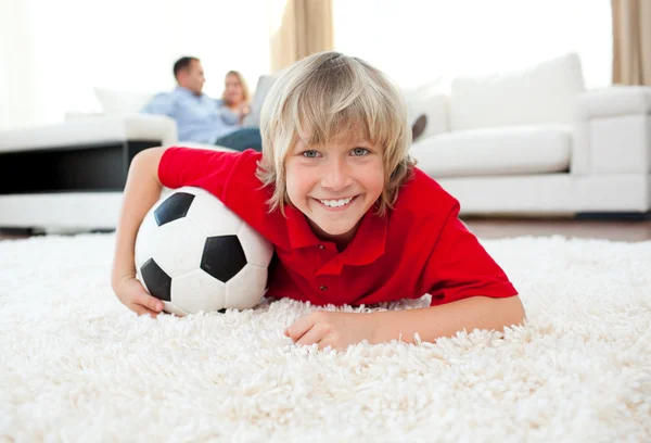 Garoto sorrindo assistindo jogo de futebol deitado no chão — Fotografia de Stock