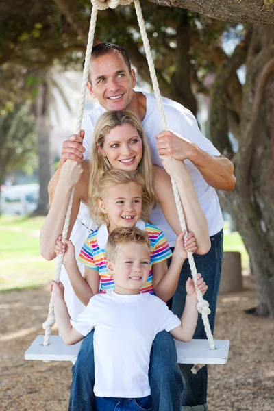 Cheerful family swinging — Stock Photo, Image