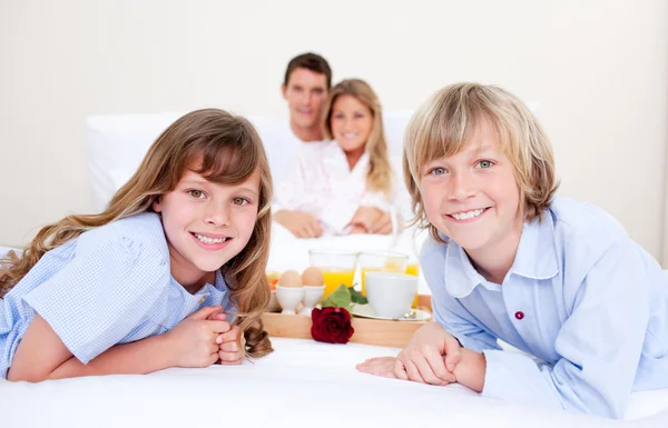 Família alegre tomando café da manhã sentado na cama — Fotografia de Stock
