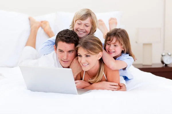 Família amorosa olhando para um laptop deitado na cama — Fotografia de Stock