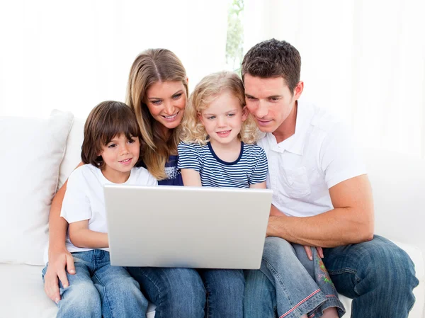 Портрет веселой семьи с ноутбуком, сидящим на диване — стоковое фото