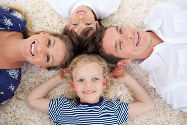 Sorridente giovane famiglia sdraiata sul pavimento — Foto Stock
