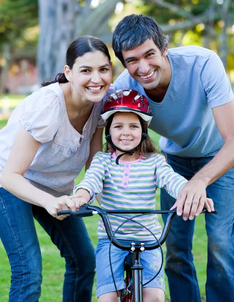 Niña aprendiendo a andar en bicicleta con sus padres —  Fotos de Stock