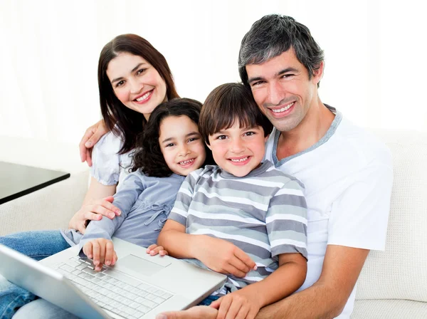 幸福的家庭使用一台笔记本电脑，坐在沙发上 — 图库照片