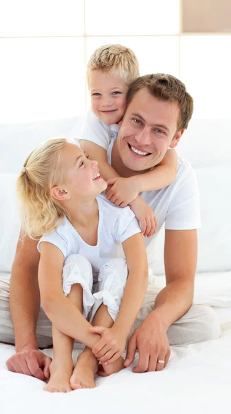 Caring father with his children sitting on bed — Stock Photo, Image