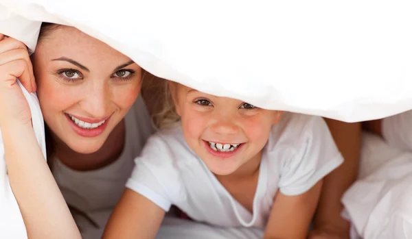 Happy mother and her blond girl playing together on a bed — Stock Photo, Image
