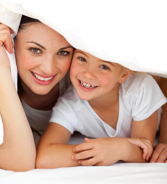 Cheerful mother and her little girl playing together on a bed — Stock Photo, Image