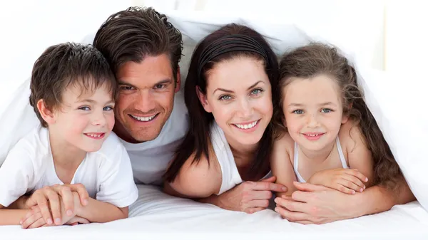 Портрет усміхненої сім'ї, що лежить на ліжку — стокове фото