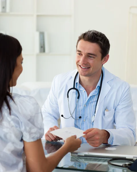 Uśmiechający się lekarz daje receptę na jego pacjentki — Zdjęcie stockowe
