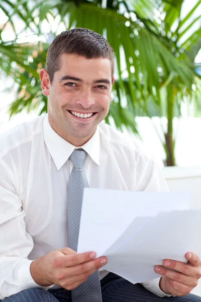 Uśmiechający się biznesmen czytanie niektórych dokumentów na kanapie — Zdjęcie stockowe