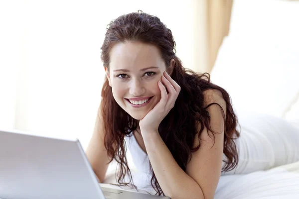 Güzel bir kadın yatakta bir dizüstü bilgisayar kullanarak — Stok fotoğraf