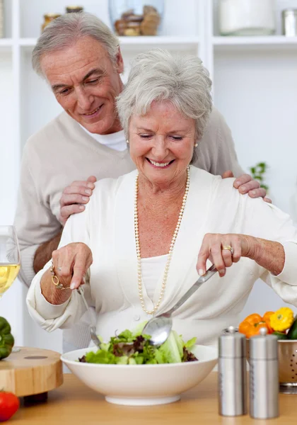 Heureux couple de personnes âgées mangeant une salade dans la cuisine — Photo