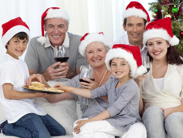 Famille boire du vin et manger des bonbons à Noël — Photo