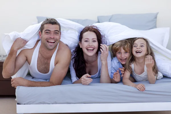 Молодая семья играет в постели вместе — стоковое фото