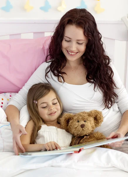 Happy mother and daughter reading in bed — Stock Photo, Image