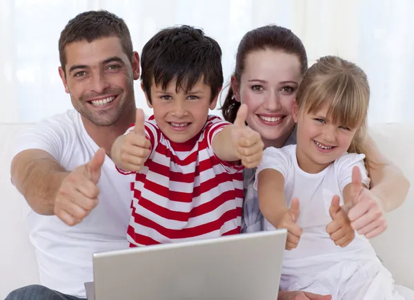 Família em casa usando um laptop com polegares para cima — Fotografia de Stock