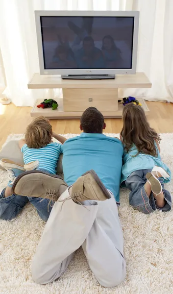 Rodina na podlaze v obýváku sledují televizi — Stock fotografie