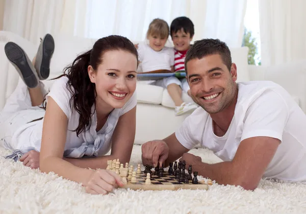 Ευτυχισμένο ζευγάρι παίζει σκάκι στον όροφο και στο καθιστικό — Φωτογραφία Αρχείου