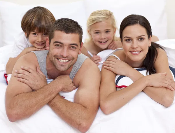 Família feliz brincando na cama dos pais — Fotografia de Stock