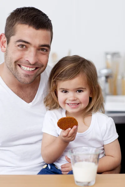 Отец и дочь едят печенье с молоком — стоковое фото
