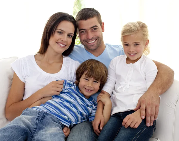 Uśmiechnięta młoda rodzina siedzi na kanapie — Zdjęcie stockowe