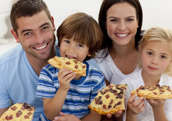 Портрет семьи, поедающей пиццу в гостиной — стоковое фото
