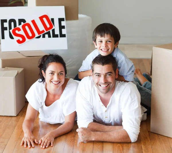 Familia en el suelo sonriendo a la cámara después de comprar casa —  Fotos de Stock