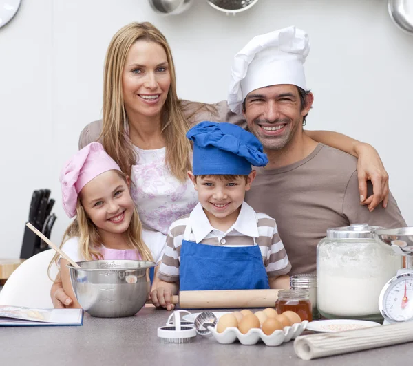 Lachende ouders helpen kinderen bakken in de keuken — Stockfoto