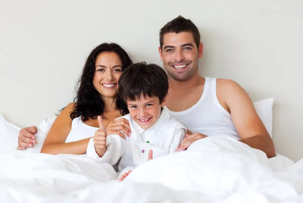 Retrato de un hijo con pulgares hacia arriba y sus padres en la cama —  Fotos de Stock