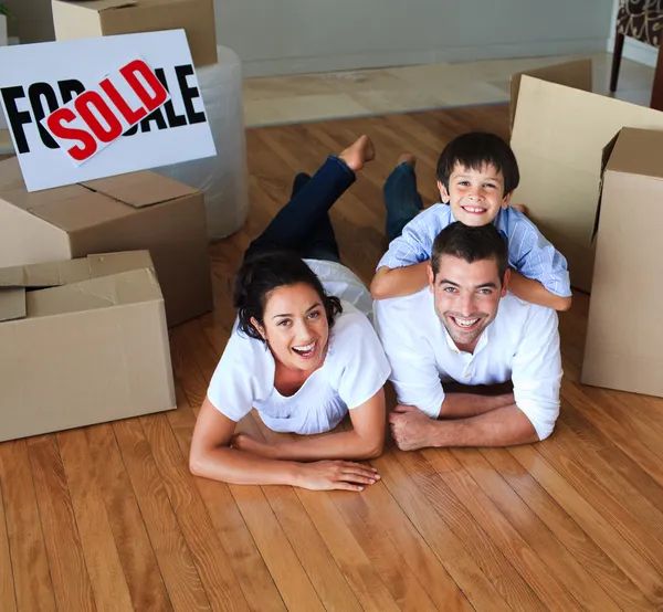 Família movendo casa no chão sorrindo para a câmera — Fotografia de Stock