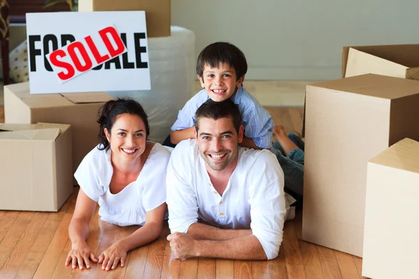 Familia en su nueva casa acostada en el suelo con cajas —  Fotos de Stock