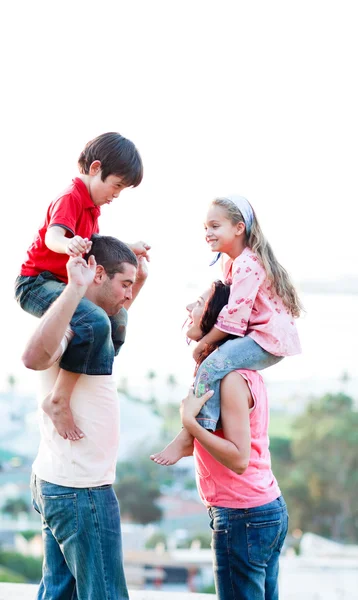 Pais dando seus filhos passeios de piggyback — Fotografia de Stock