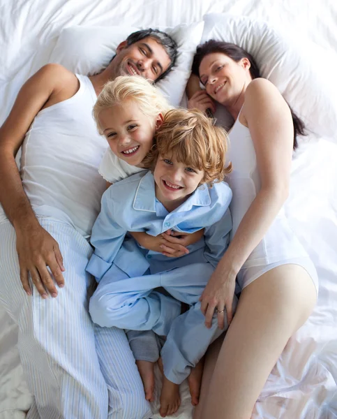 Glada föräldrar och barn tillsammans på sängen — Stockfoto