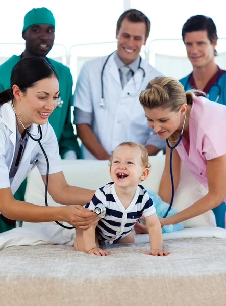 Bebekle hastanede tıbbi ekip gülümseyen — Stok fotoğraf