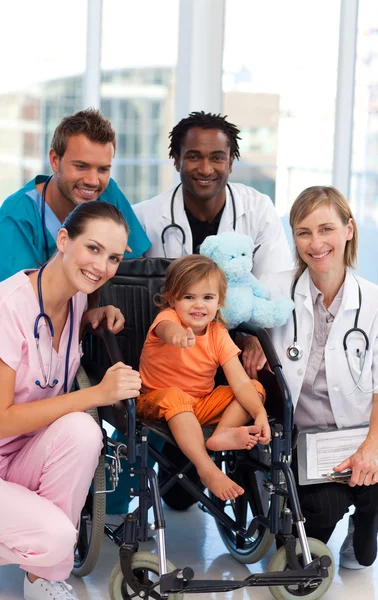 Baby girl in a wheelchair with medical team — Stock Photo, Image