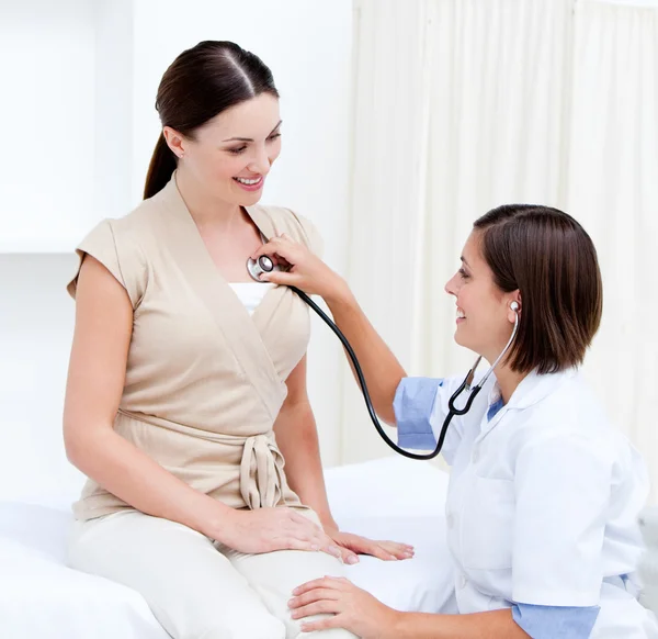 Женщина-врач осматривает улыбающуюся пациентку со своим ститом — стоковое фото