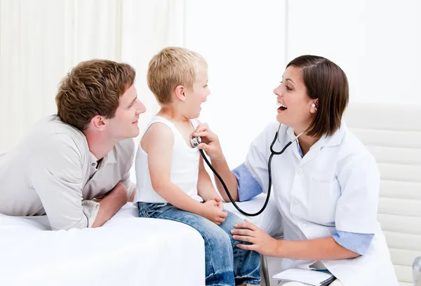 Médica radiante examinando um menino com seu pai — Fotografia de Stock