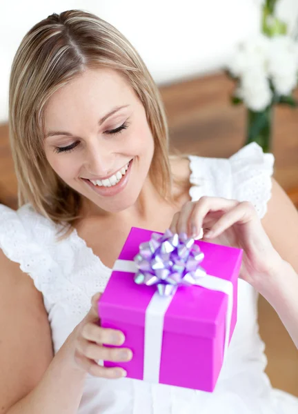 Katta oturan bir hediye açılış memnun kadın — Stok fotoğraf