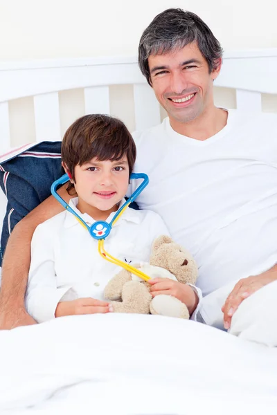Padre sorridente e suo figlio malato che giocano con uno stetoscopio — Foto Stock