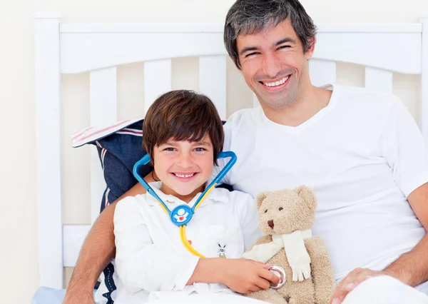 Fröhlicher Vater und sein kranker Sohn spielen mit einem Stethoskop — Stockfoto