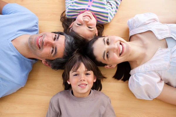 Sorridente giovane famiglia sdraiata sul pavimento con la testa insieme — Foto Stock